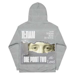 May include: A gray hoodie with a graphic print of a face peeking out from behind a torn piece of paper. The text "11:11AM" is printed above the face, and the text "ONE POINT TWO the Level" is printed below the face. The text "MADRINA DORMO BENE DI NOTTE" is printed on the right side of the graphic.