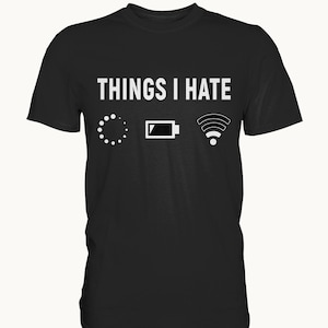 Könnte beinhalten: Schwarzes T-Shirt mit dem weißen Text „THINGS I HATE“ über drei weißen Symbolen: einem Ladesymbol, einem Batteriesymbol und einem WLAN-Symbol. Das Shirt hat einen Rundhalsausschnitt.