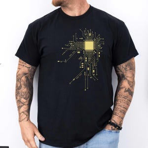 Könnte beinhalten: Schwarzes T-Shirt mit einem goldenen Schaltkreisdesign. Das Design zeigt einen zentralen Prozessorchip und eine komplizierte Verdrahtung.