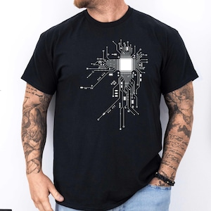 Könnte beinhalten: Ein schwarzes T-Shirt mit einem weißen Aufdruck eines Schaltkreisdesigns. Das Design zeigt eine zentrale Verarbeitungseinheit (CPU) mit Verbindungsleitungen.