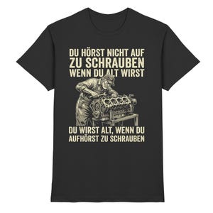 Könnte beinhalten: Schwarzes T-Shirt mit einer Grafik eines Mechanikers, der an einem Motor arbeitet. Der Text lautet "DU HÖRST NICHT AUF ZU SCHRAUBEN WENN DU ALT WIRST" und "DU WIRST ALT, WENN DU AUFHÖRST ZU SCHRAUBEN" in Weiß.