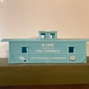 May include: A light blue model train caboose with the text "K-Line Salutes the UNC Tarheels 1993 National Champions 77-71" printed on the side.