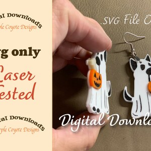 May include: A pair of white ghost earrings with black details, holding orange jack-o'-lantern buckets. The earrings are laser tested and are available as a digital download in SVG format. "Digital Downloads Purple Coyote Designs" and ".svg File Only" are written on the image.