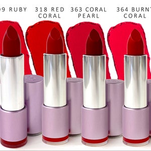 Puede incluir: Cuatro tubos de lápiz labial con diferentes tonos de rojo, incluyendo rubí, coral rojo, coral perla y coral quemado. Los tubos de lápiz labial son plateados con una base morada.