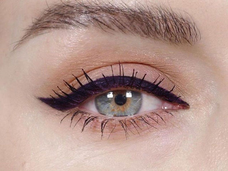 Peut inclure: Gros plan sur l'&oelig;il d'une femme avec un eye-liner noir &eacute;pais en forme d'aile. L'eye-liner est appliqu&eacute; avec pr&eacute;cision et s'&eacute;tend au-del&agrave; du coin externe de l'&oelig;il.