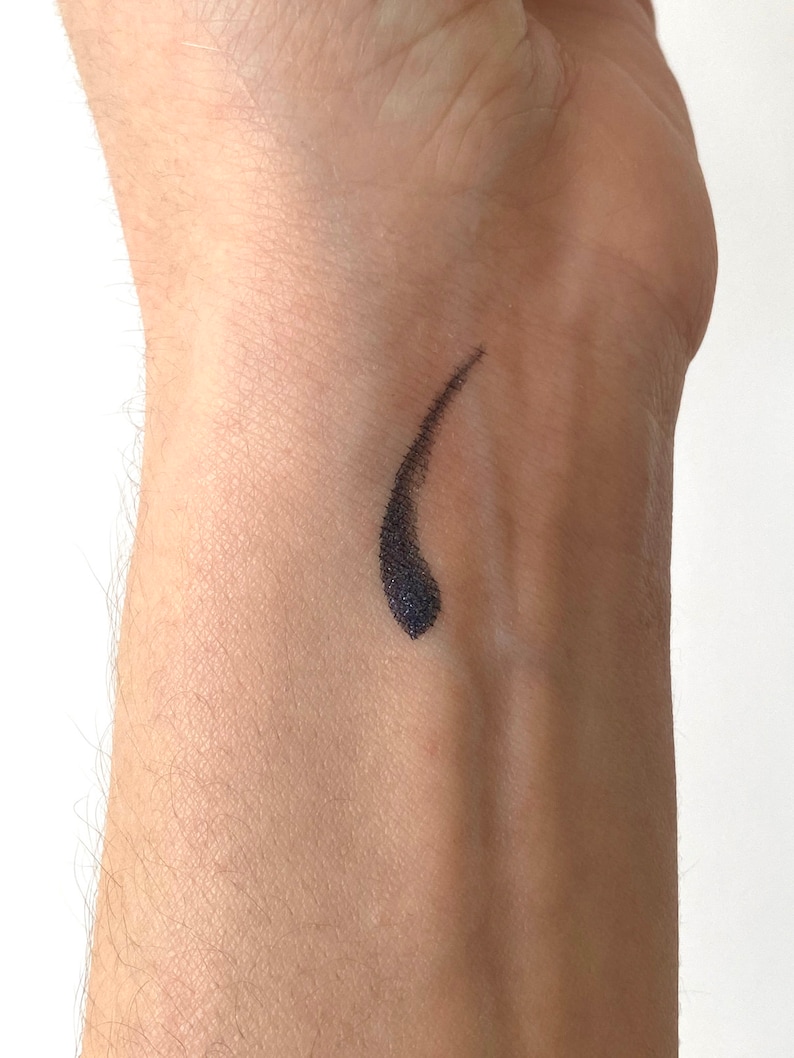Peut inclure: Gros plan sur le poignet d'une personne avec un trait d'eye-liner noir en forme de larme.