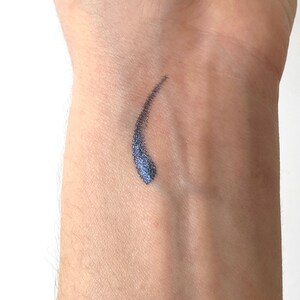 Peut inclure: Un gros plan sur le poignet d'une personne avec un petit &eacute;chantillon de traceur liquide bleu fonc&eacute; et chatoyant appliqu&eacute; sur la peau.