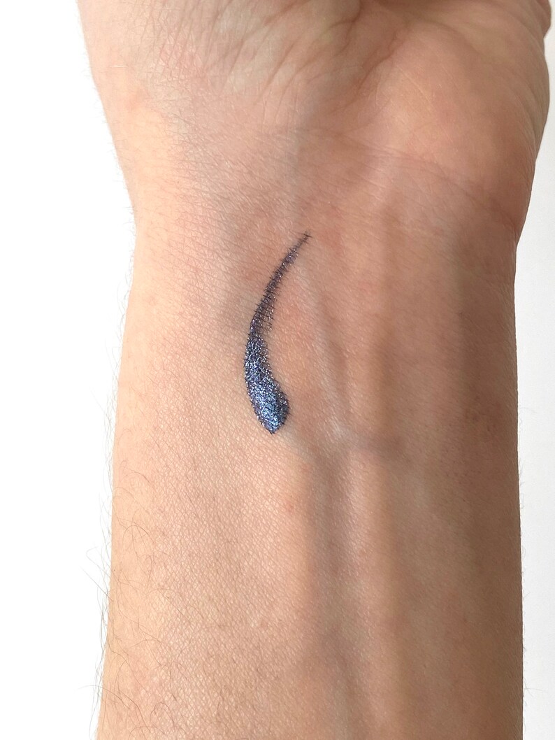Peut inclure: Un gros plan sur le poignet d'une personne avec un petit &eacute;chantillon de traceur liquide bleu fonc&eacute; et chatoyant appliqu&eacute; sur la peau.