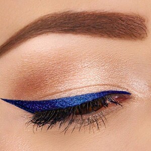 Peut inclure: Gros plan sur un &oelig;il avec un eye-liner bleu fonc&eacute; en forme d'aile. L'&oelig;il est entour&eacute; de fards &agrave; paupi&egrave;res neutres.