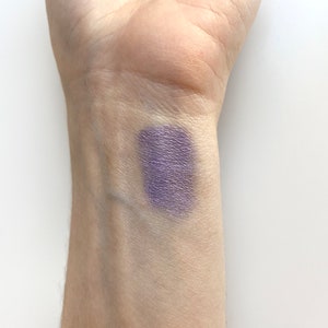 May include: A swatch of purple eyeshadow on a person's wrist.