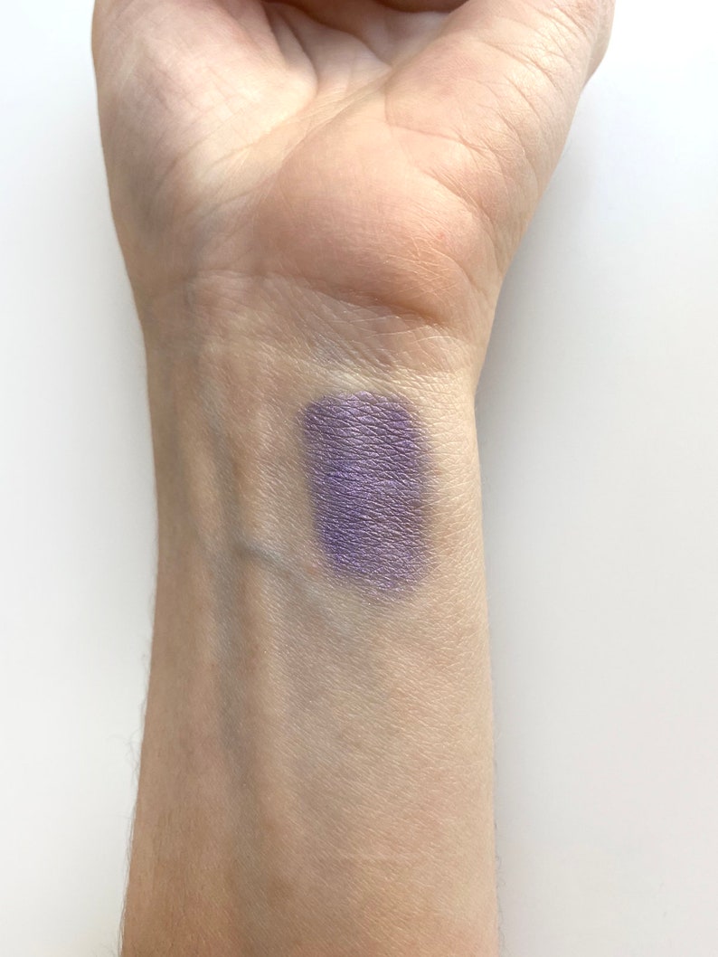 May include: A swatch of purple eyeshadow on a person's wrist.