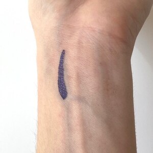 Peut inclure: Gros plan sur le poignet d'une personne avec une ligne de couleur violet fonc&eacute; trac&eacute;e dessus.