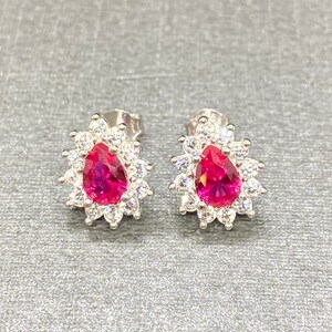 K&ouml;nnte beinhalten: Ein Paar silberne Ohrringe mit einem birnenf&ouml;rmigen rosa Stein, der von kleineren wei&szlig;en Steinen umgeben ist.