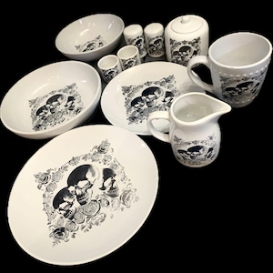 Puede incluir: Un juego de platos de cerámica blanca con un diseño de calavera negra y flores. El juego incluye una jarra, un azucarero, dos cuencos pequeños, dos cuencos grandes y una taza.