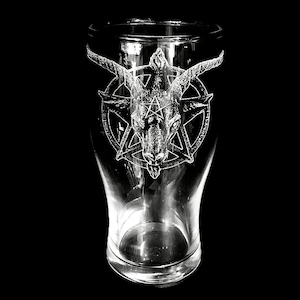 Peut inclure: Un verre à bière transparent avec un motif gravé d'une tête de chèvre dans un pentagramme. Le motif blanc se détache sur le verre. Le verre a une large ouverture et un corps légèrement incurvé, sur fond noir.