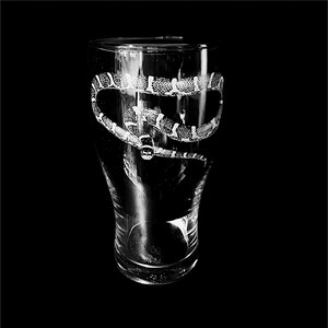 May include: A clear pint glass featuring an etched design of a snake. The snake is depicted with a pattern of black and white scales, wrapping around the glass. The background is a solid black.