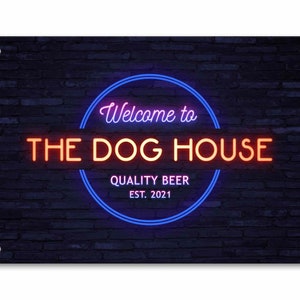 May include: Neon sign with a blue and pink glow on a black brick wall background. The sign reads "Welcome to The Dog House Quality Beer Est. 2021".