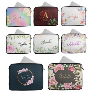 May include: A selection of laptop sleeves featuring floral designs and personalised names. The sleeves showcase a variety of floral patterns, including roses, peonies, and other blossoms. Each sleeve has a different name printed on it, such as Amelia, Ayla, Sophia, and Isabella.