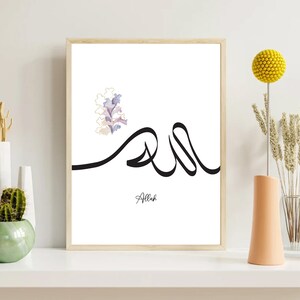 Puede incluir: Una impresi&oacute;n enmarcada en blanco con un dise&ntilde;o de caligraf&iacute;a negra de la palabra "Allah" en escritura &aacute;rabe. Un dise&ntilde;o floral de acuarela se encuentra en la esquina superior izquierda de la impresi&oacute;n.