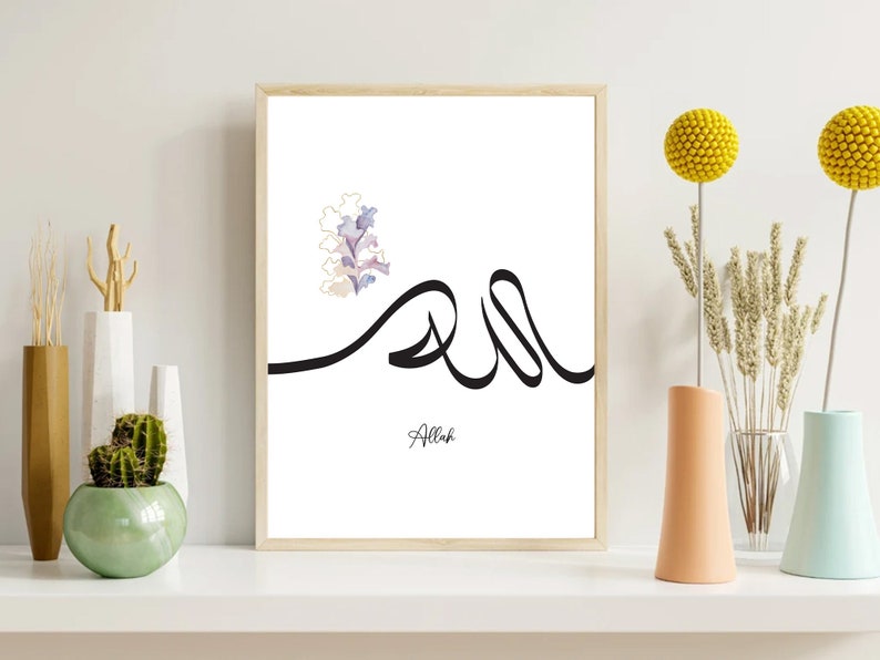 Puede incluir: Una impresi&oacute;n enmarcada en blanco con un dise&ntilde;o de caligraf&iacute;a negra de la palabra "Allah" en escritura &aacute;rabe. Un dise&ntilde;o floral de acuarela se encuentra en la esquina superior izquierda de la impresi&oacute;n.
