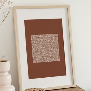 May include: A framed print with a brown background and a white geometric pattern. The frame is made of light wood.