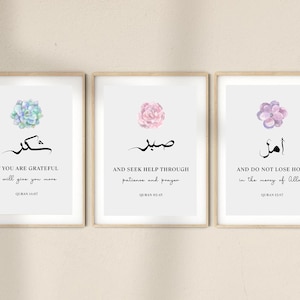 May include: Three framed prints with watercolor floral designs and Arabic calligraphy. The top print features a light blue succulent and the text "IF YOU ARE GRATEFUL I WILL GIVE YOU MORE QURAN 14:7". The middle print features a pink flower and the text "صبر AND SEEK HELP THROUGH PATIENCE AND PRAYER QURAN 62:5". The bottom print features a purple flower and the text "أمل AND DO NOT LOSE HOPE IN THE MERCY OF ALLAH QURAN 12:87".