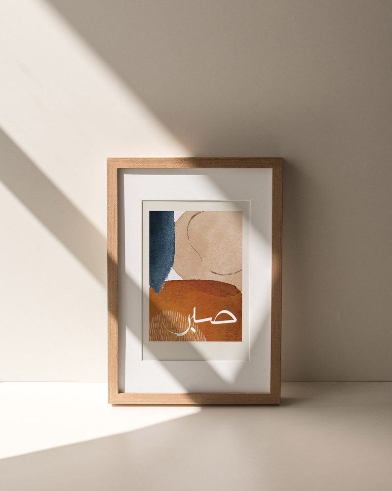 May include: A framed abstract art print with a beige, blue, and orange colour scheme. The Arabic word "حب" is written in white in the centre of the print.