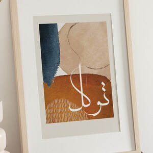 May include: A framed print with an abstract design featuring a blue, brown, and beige colour scheme. The print includes Arabic calligraphy in white.