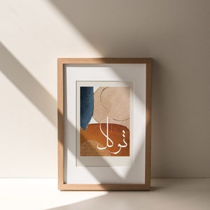 May include: A framed print featuring an abstract design in shades of blue, brown, and beige. The print includes Arabic calligraphy in white that reads "Thank you".