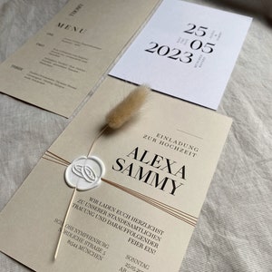 May include: A wedding invitation with a beige background and brown accents. The invitation features the names "Alexa" and "Sammy" in a bold, modern font. The text reads "We invite you to our wedding ceremony and reception on Sunday, May 25, 2023 at 1 p.m. at Schloss Nymphenburg, Nordliche Stra&szlig;e 5, 81544 M&uuml;nchen."