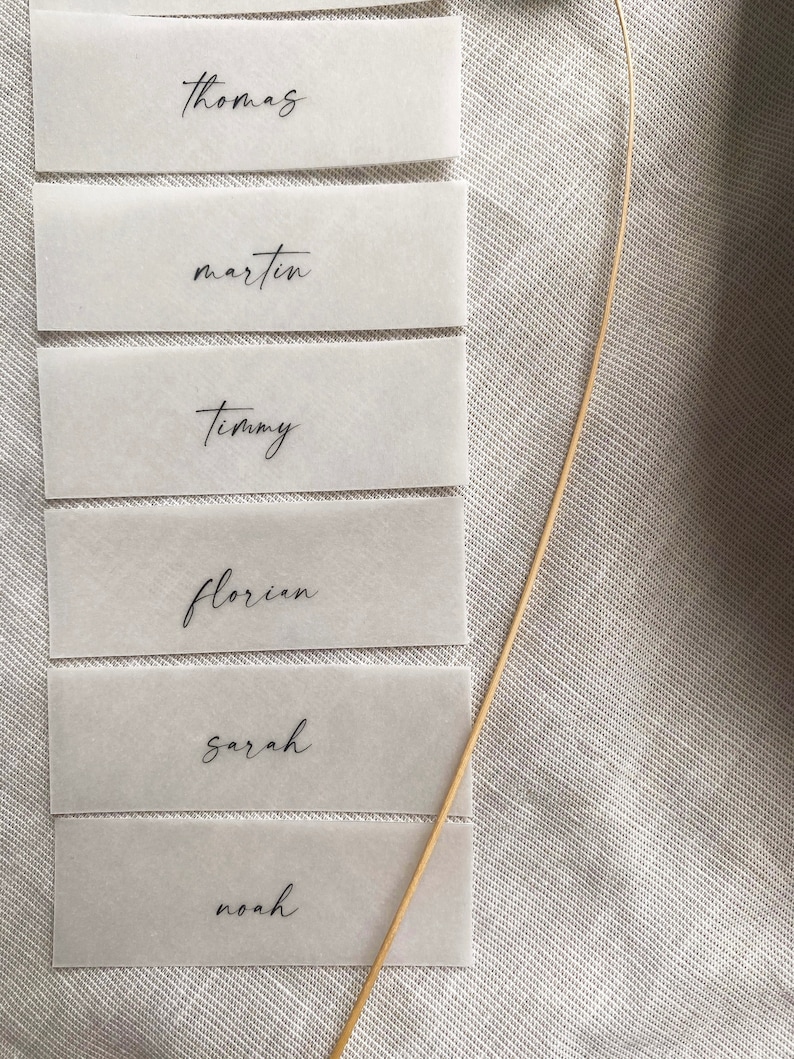 Puede incluir: Seis tarjetas de lugar blancas con nombres en caligraf&iacute;a negra: Thomas, Martin, Timmy, Florian, Sarah y Noah.
