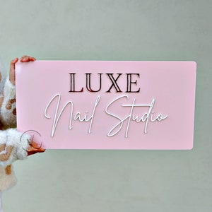 Custom Rectangle acrylic business sign in bubble gum pink backing, LUXE  in 3D rose gold acrylic on the top, Nail studio on 3D white acrylic under it in cursive font