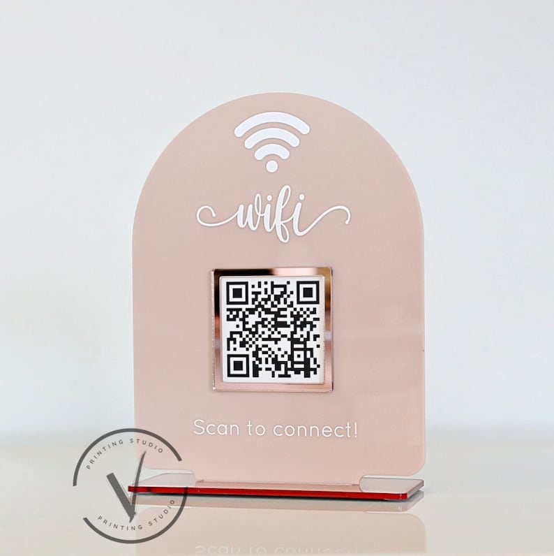 May include: A pink acrylic sign with a white wifi symbol and the word "wifi" in cursive. A rose gold square with a QR code is in the centre of the sign. The text "Scan to connect!" is below the QR code.