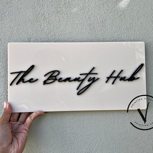 Custom Rectangle acrylic business sign in beige  colour, THE BEAUTY HUB in cursive font displayed on the middle in 3D gloss black acrylic