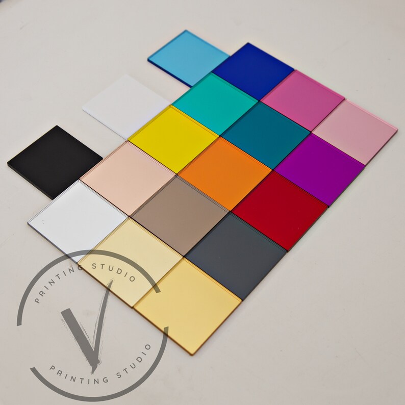 May include: A collection of 16 colour samples, including black, white, gold, silver, red, orange, yellow, green, blue, pink, purple, and brown. The samples are arranged in a grid pattern on a white surface.