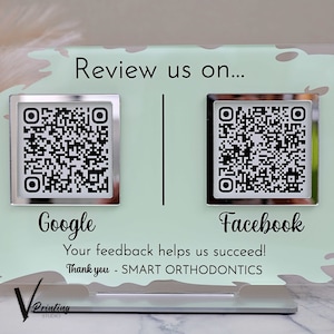 May include: Transparent acrylic sign featuring QR codes for Google and Facebook reviews. The sign has a pale green background with the text "Review us on..." and "Your feedback helps us succeed!" The sign is for Smart Orthodontics.