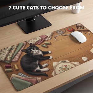 May include: A rectangular desk mat featuring a black and white cat lying on a wooden surface surrounded by sewing supplies including fabric scraps, spools of thread, a measuring tape, a pincushion, and an embroidery hoop. Text reads: 7 CUTE CATS TO CHOOSE FROM.