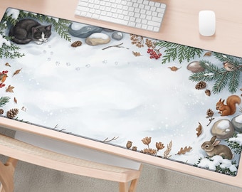 May include: A rectangular desk mat featuring a winter forest scene with a black and white cat, a brown squirrel, and a rabbit. The illustration includes snow-covered ground, pine branches, pinecones, red berries, and smooth gray stones.