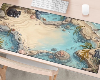 May include: A rectangular desk mat featuring a detailed illustration of a sandy beach scene with tide pools, a black and white cat, small fish, a starfish, seashells, and two shorebirds. The mat is positioned on a wooden desk with a keyboard and mouse.