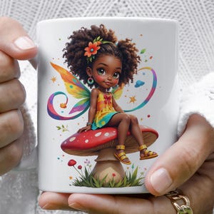 A person is holding a white mug with a colorful illustration of a fairy sitting on a mushroom.