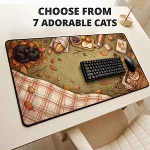 May include: A rectangular desk mat featuring an autumn picnic scene with a black cat, fallen leaves, a plaid blanket, bread, fruit, and a small mouse. A black keyboard and mouse sit on the mat. Text reads: CHOOSE FROM 7 ADORABLE CATS.