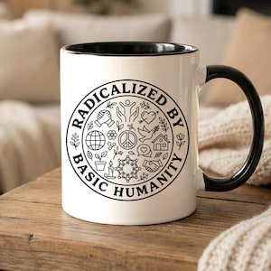 May include: White ceramic mug with a black interior and handle. The mug features a circular design with the words "RADICALIZED BY BASIC HUMANITY" and various small illustrations in black.