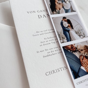 May include: A white card with black text that reads "VON GANZ DAN... f&uuml;r so viel Liebe Taten und Geschenke Es bedeutet dass so viele gro an diesem Tag an Es war f&uuml;r uns eine u an die wir un Dankbarkeit zur&uuml; CHRISTIN CHRISTI 23". The card has three photos attached to it with a silver heart-shaped paper clip.