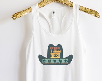 May include: White tank top with a retro-style graphic of a cowboy hat with the text "Y'all Need Groundwork" in a rainbow color scheme.