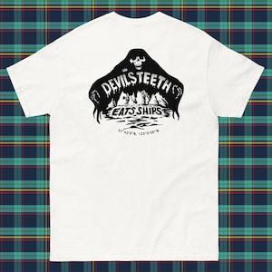 Puede incluir: Camiseta blanca con un gráfico negro de un fantasma con el texto "the DEVILS TEETH EATS SHIPS" y las coordenadas "37°42'0"N 123°0′48″W".