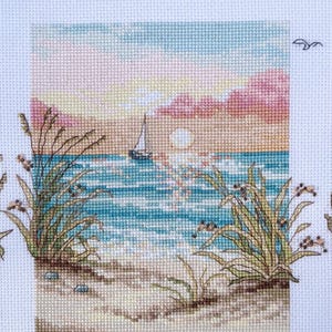 May include: Cross-stitch of a coastal scene at sunset. The image features a sailboat on the water, with the sun setting in the background. The foreground includes beach grass and sand, with a sky of pink, blue, and yellow.