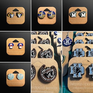 May include: Assortment of handmade earrings featuring various school logos and mascots. The logos include a hockey club, a horse, a ram, a lightning bolt, and a number 34. The earrings are displayed on brown card stock with the text "Twisted Roots Maker" printed on the bottom.