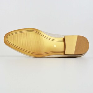 May include: The bottom of a cream-colored flat shoe with a gold sole. The sole has a textured pattern and the number "8" is printed on the sole.