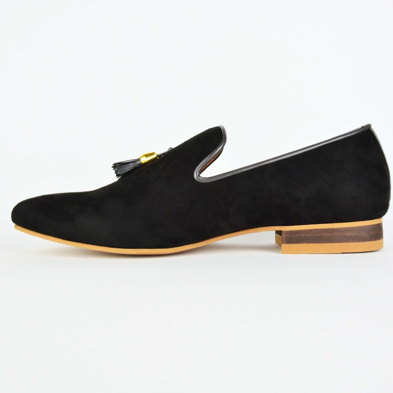May include: Black suede loafers with a gold tassel and a brown leather sole.