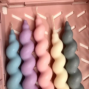 May include: Five spiral candles in a variety of colors, including light blue, lavender, pink, cream, and gray. The candles are arranged in a row and are all the same size.